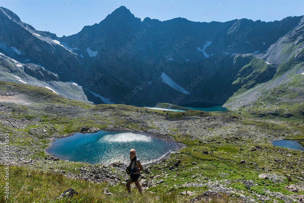 Woman hiking with a camera in the Caucasus mountains. Summer landscape with mountain lakes. Traveling in the Caucasus, Russia