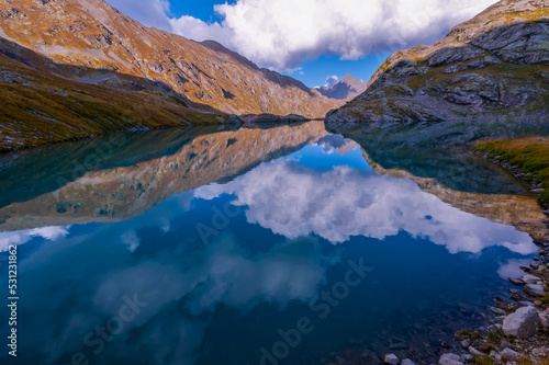 Dramatic view turquoise mountain lake surrounded by rocks and mountains with snow melt. Autumn landscape, clear blue sky. Traveling in the Caucasus, Russia