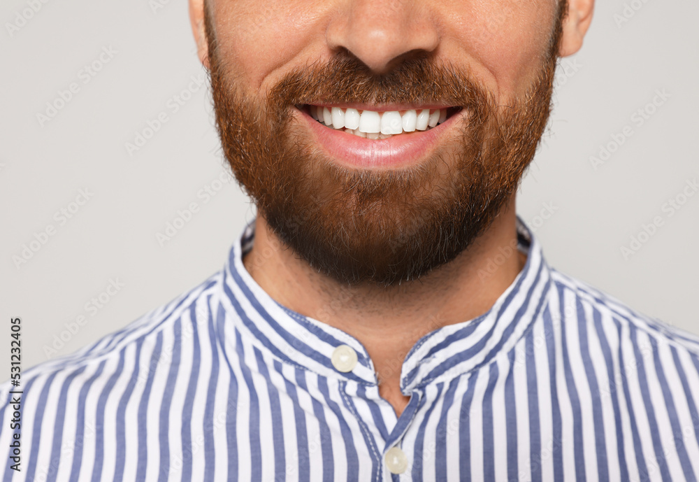 Obraz premium Smiling man with beard on grey background, closeup