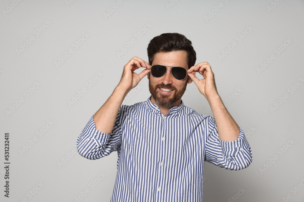 Fototapeta premium Portrait of smiling bearded man with sunglasses on grey background
