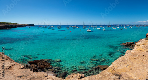 Panoramic view of Cala Saona with sailboats anchored in the Mediterranean Sea