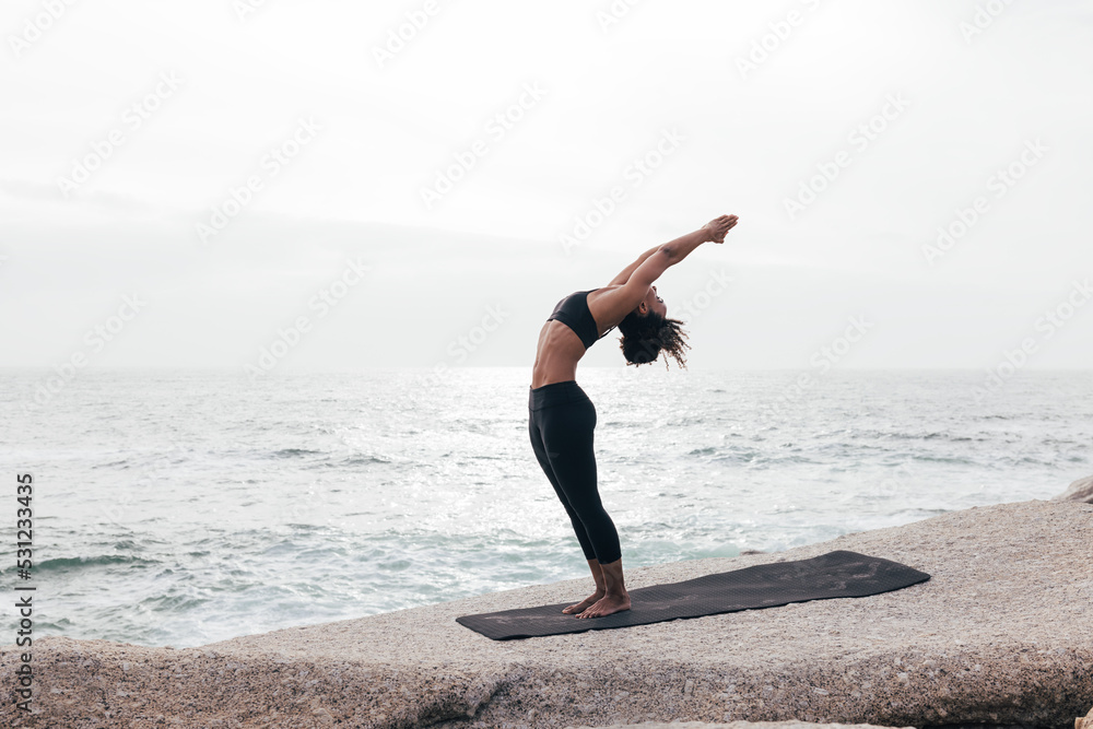 Woman in Standing Backbend Pose by ocean Woman in Standing Backbend Pose by ocean