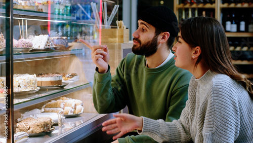 young couple very charismatic at the coffee shop looking at the showcase fridge and choose the favourite dessert