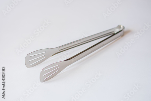 chromed kitchen tongs on an isolated white background