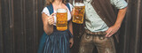 Oktoberfest, woman and man in Bavarian costume with beer mugs