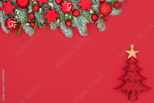 Magical Christmas winter fir and snow red background border composition with baubles and tree decoration. Festive fun design for traditional Xmas holiday season.