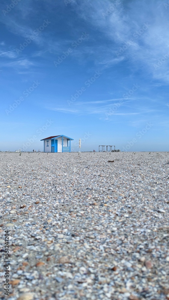 Obraz premium Empty beach with a single blue sea house under clear blue sky