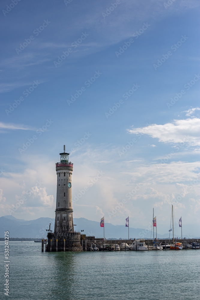 White big lighthouse on the Bodensee Lindau Germany with pier and flags reflecting in the water