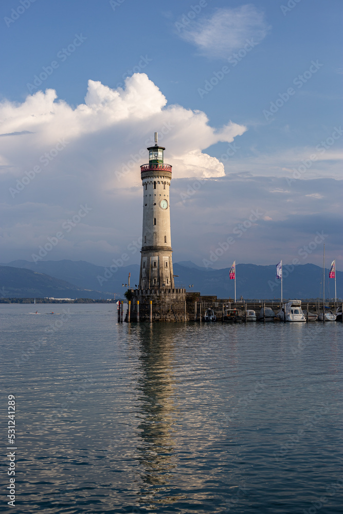 White big lighthouse on the Bodensee Lindau Germany with pier and flags reflecting in the water