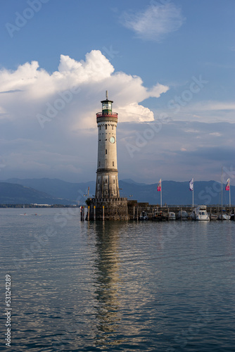 White big lighthouse on the Bodensee Lindau Germany with pier and flags reflecting in the water