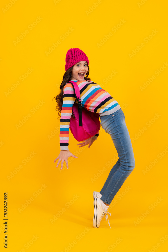 Schoolgirl child student with backpack and warn hat, isolated yellow background. Learning and knowledge education concept. Happy teenager, positive and smiling emotions of teen schoolgirl.