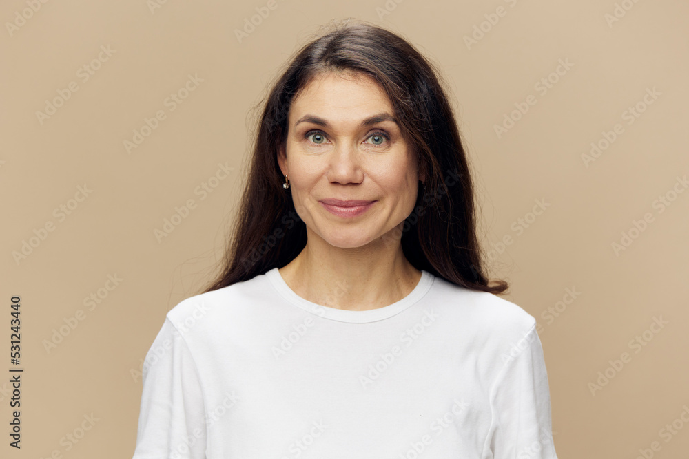 a beautiful, surprised woman stands in a white T-shirt on a beige background, holding her hands near her face a beautiful, surprised woman stands in a white T-shirt on a beige background, holding her hands near her face
