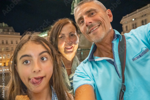 Happy family of three people taking selfie visiting the city at night