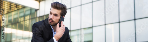 Young businessman talking on the phone in front of corporate office building