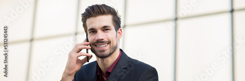 Young businessman talking on the phone in front of corporate office building