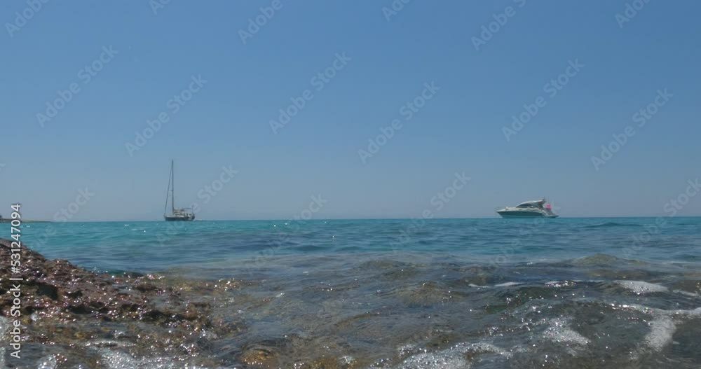Seascape with sailboat at beautiful bay, pleasure of sailing. Clear blue sky on a sunny day. View from sea water level. Summer travel holidays concept. Slow motion 4K footage. Seascape with sailboat at beautiful bay, pleasure of sailing. Clear blue sky on a sunny day. View from sea water level. Summer travel holidays concept. Slow motion 4K footage.