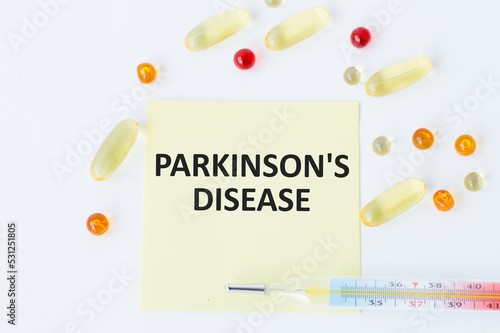 Parkinson's Disease text is on a card on a white background around scattered tablets and lies termemtra. Medical concept