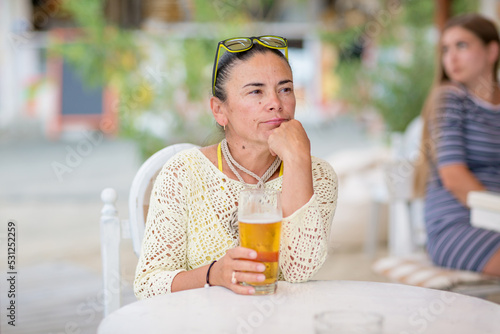 Portrait of beautiful young woman drinking beer at beach cafe and enjoying summer day