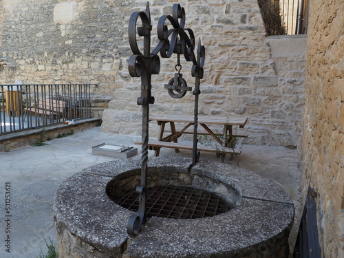 pozo de agua de origen medieval construido en piedra color gris, forma circular, polea de hierro color negro, lérida, españa, europa