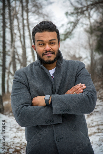 Arab man enjoying snowflakes falling from above in the forest photo