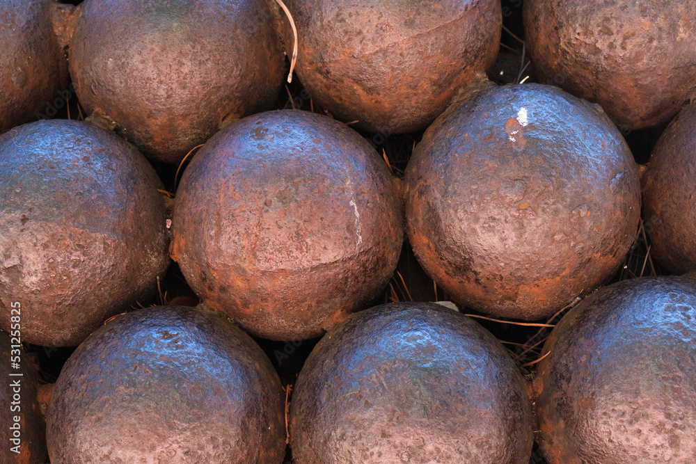 Closeup of ancient and rusty cannon balls, pattern, iron sphere shape cannonball texture, a stack of round metal balls, war ammunition, background. Closeup of ancient and rusty cannon balls, pattern, iron sphere shape cannonball texture, a stack of round metal balls, war ammunition, background.