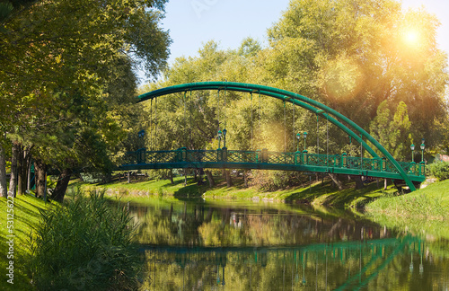 Fotografia A green bridge accross the river in the park