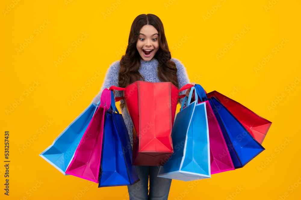 Amazed teenager. Beautiful fashion teenager child girl with shopping bags on yellow background. Shopaholic shopping and fashion. Kid with shopping sale bags. Excited teen girl.