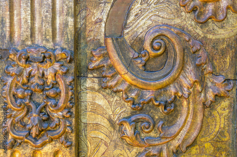 Background of a gilded wooden iconostasis made in the 16th century. The ancient carved iconostasis of the 16th century in Perm is decorated with patterns, images of animals and angels.Religious images