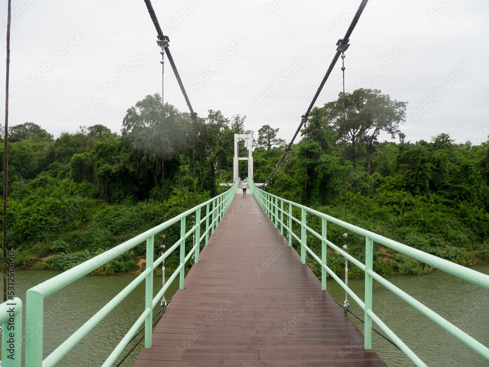 The green light handrail with a brown walkway and white suspension bridge at Sirindhorn District, Ubon Ratchathani Province, Thailand.