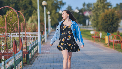 A cheerful girl walks along the city promenade.