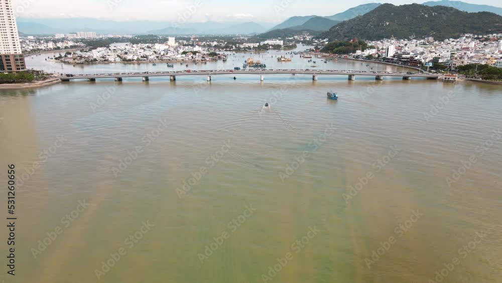 The harbor of the Vietnamese city of Nha Trang standing on the seashore with boats and bridge, a view from a drone The harbor of the Vietnamese city of Nha Trang standing on the seashore with boats and bridge, a view from a drone