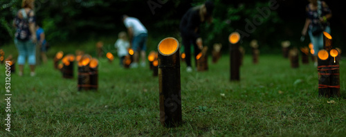 Hundreds of Japanese bamboo lanterns - candles in bamboo stands - flickeringly illuminate the dark, in the style of the traditional Japanese festival of lights Tatsunokuchi Take-toro photo