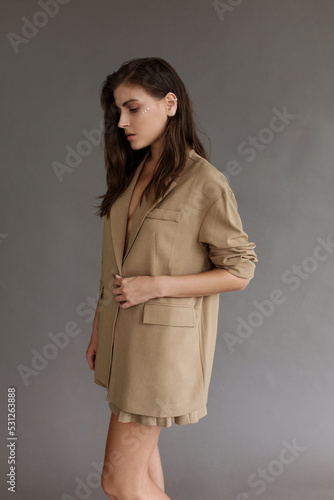 Beautiful fashion woman with make up standing posing , wearing brown jacket and skirt.