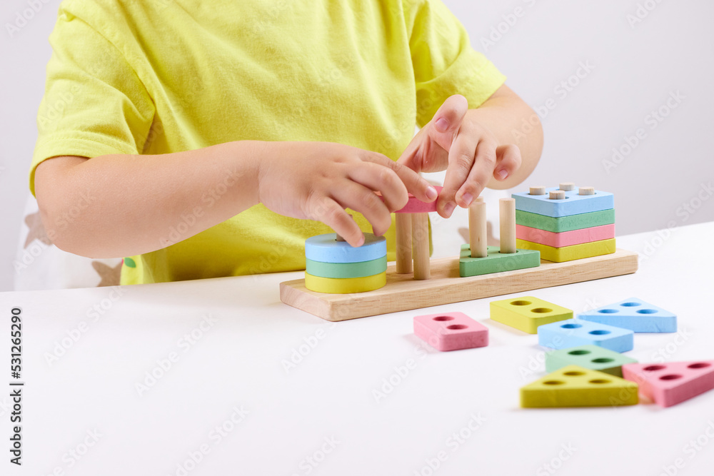 The child plays with colorful toy blocks. eco wooden toys. Little smart child playing natural toys. games for early development. Toy in children's hands close-up. selective focus The child plays with colorful toy blocks. eco wooden toys. Little smart child playing natural toys. games for early development. Toy in children's hands close-up. selective focus