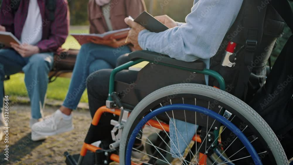 Man sits in wheelchair learning subject with friends Man sits in wheelchair learning subject with friends