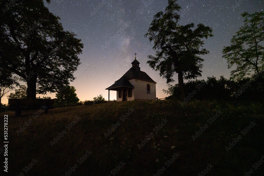 Fototapeta premium Milchstraße Sternenhimmel über Kirche Kapelle Kleine Kalmit im Sternenpark Pfälzerwald