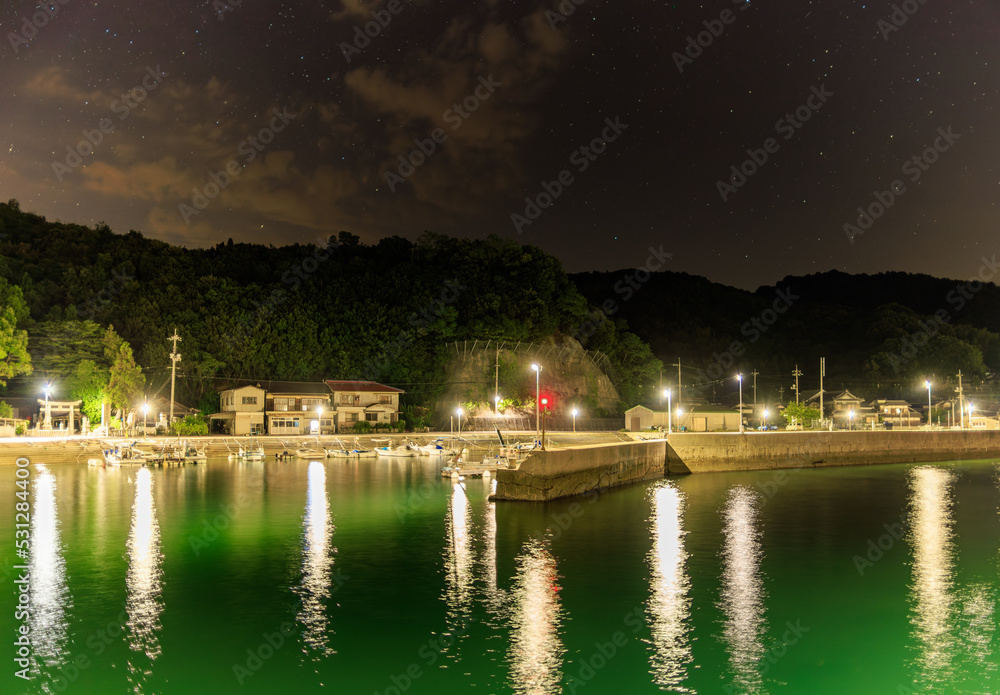 Quiet harbor in small coastal village under starry night sky Quiet harbor in small coastal village under starry night sky