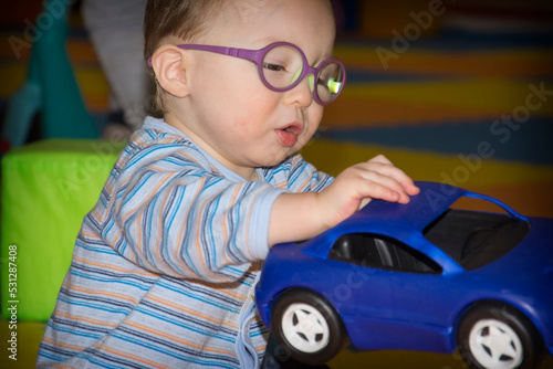 A little boy with glasses plays with a typewriter in the playroom.