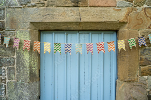 Old bunting hanging above the door of an old stone cottage