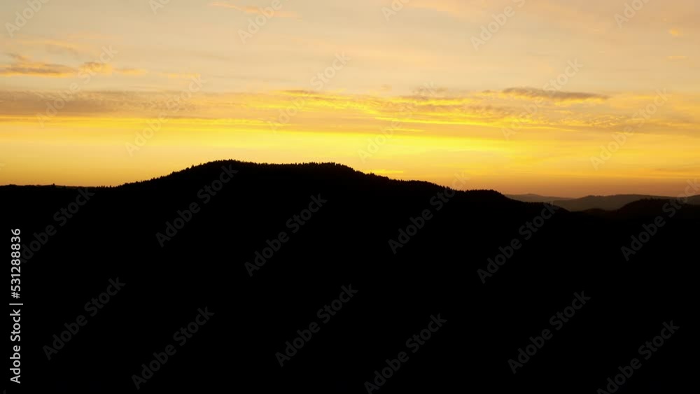 Aerial birdseye view mountains at sunset. Picturesque dark black mountains with forest under red colorful evening sky. Drone flight. Travel. Aerial birdseye view mountains at sunset. Picturesque dark black mountains with forest under red colorful evening sky. Drone flight. Travel.