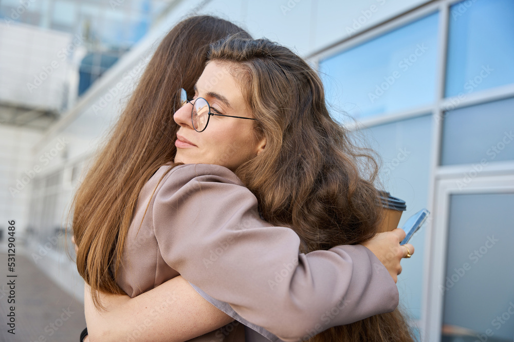 Two young women is hugging each other on the street
