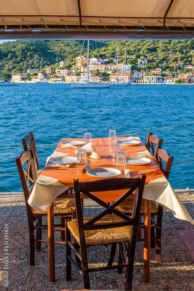 Fototapeta premium Reserved table in Greek tavern in Vathy in the picturesque port of Vathy village, the capital of Ithaca island, Ionian, Greece.
