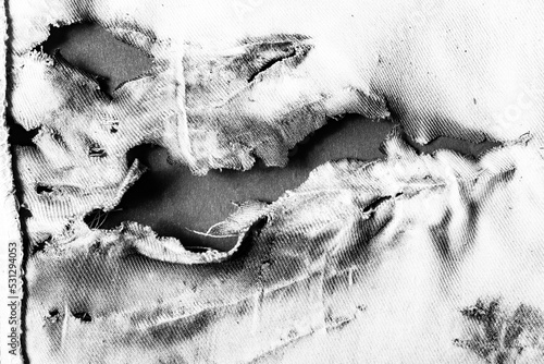 Bild auf Leinwand Close-up black and white texture photo of torn, burned and damaged cloth