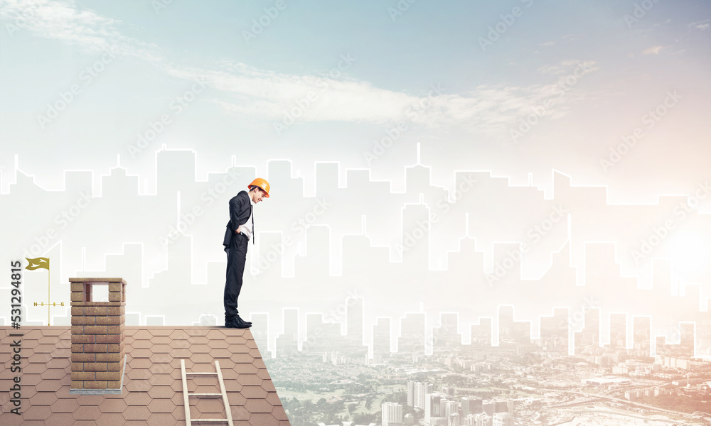 Engineer man standing on roof and looking down. Mixed media Engineer man standing on roof and looking down. Mixed media