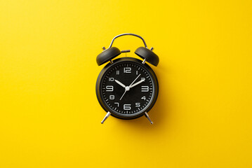 Black friday concept. Top view photo of black alarm clock on isolated yellow background