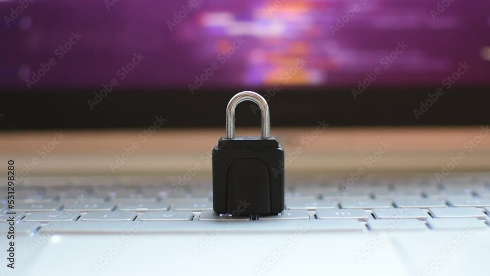Locked padlock on top of laptop. A purple digital pattern is seen on the background 