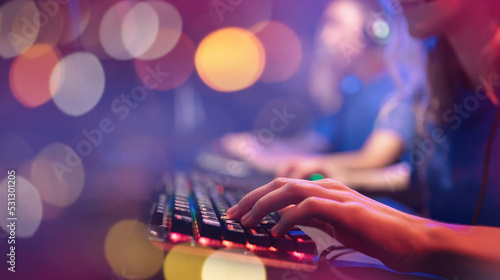 Professional cyber video gamer studio room with personal computer armchair, keyboard woth woman hand for stream in neon color blur background banner