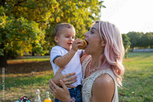 Mother eats an apple given by her son during a picnic, healthy eating concept