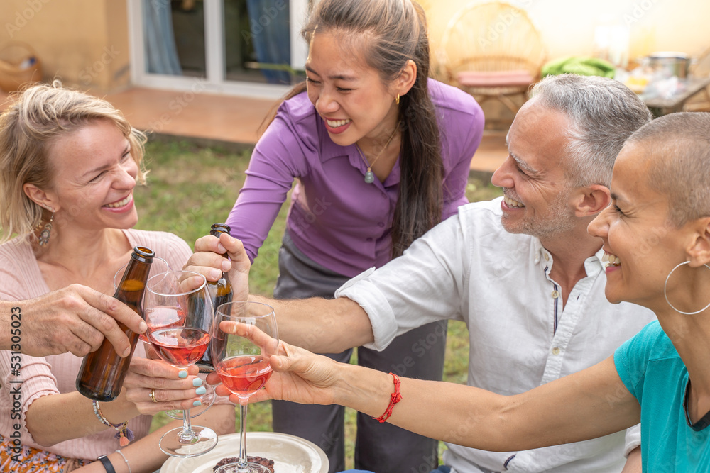 Friends toasting with beautiful smile around the table at house patio diner.