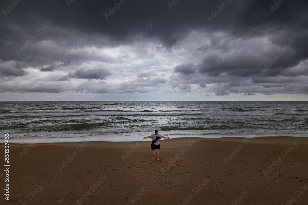 Girl at the beach in front of a storm